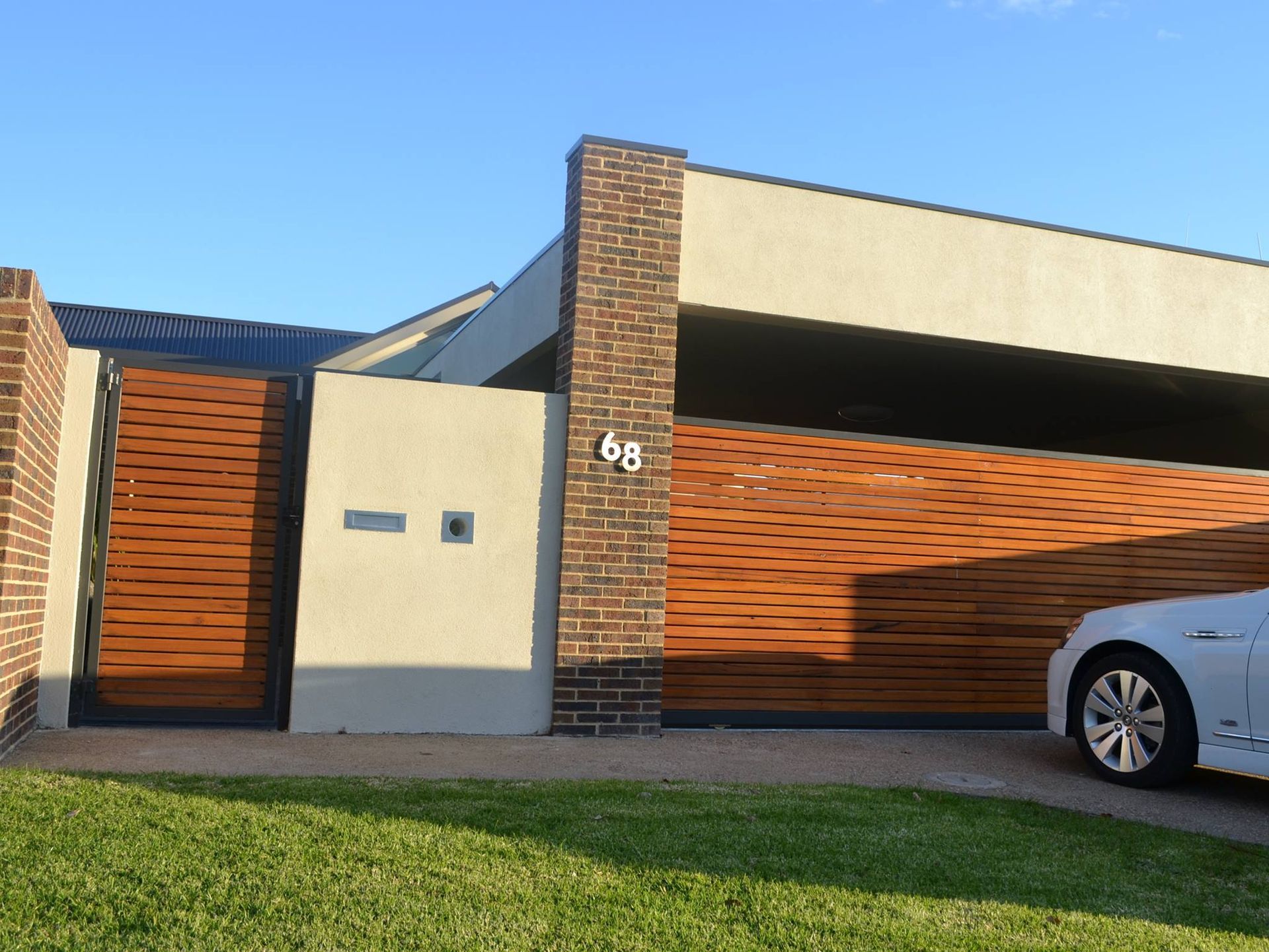 A Car Is Parked In Front Of A House With A Wooden Gate – East Gippsland, VIC - East Gippsland Garage Doors & Maintenance