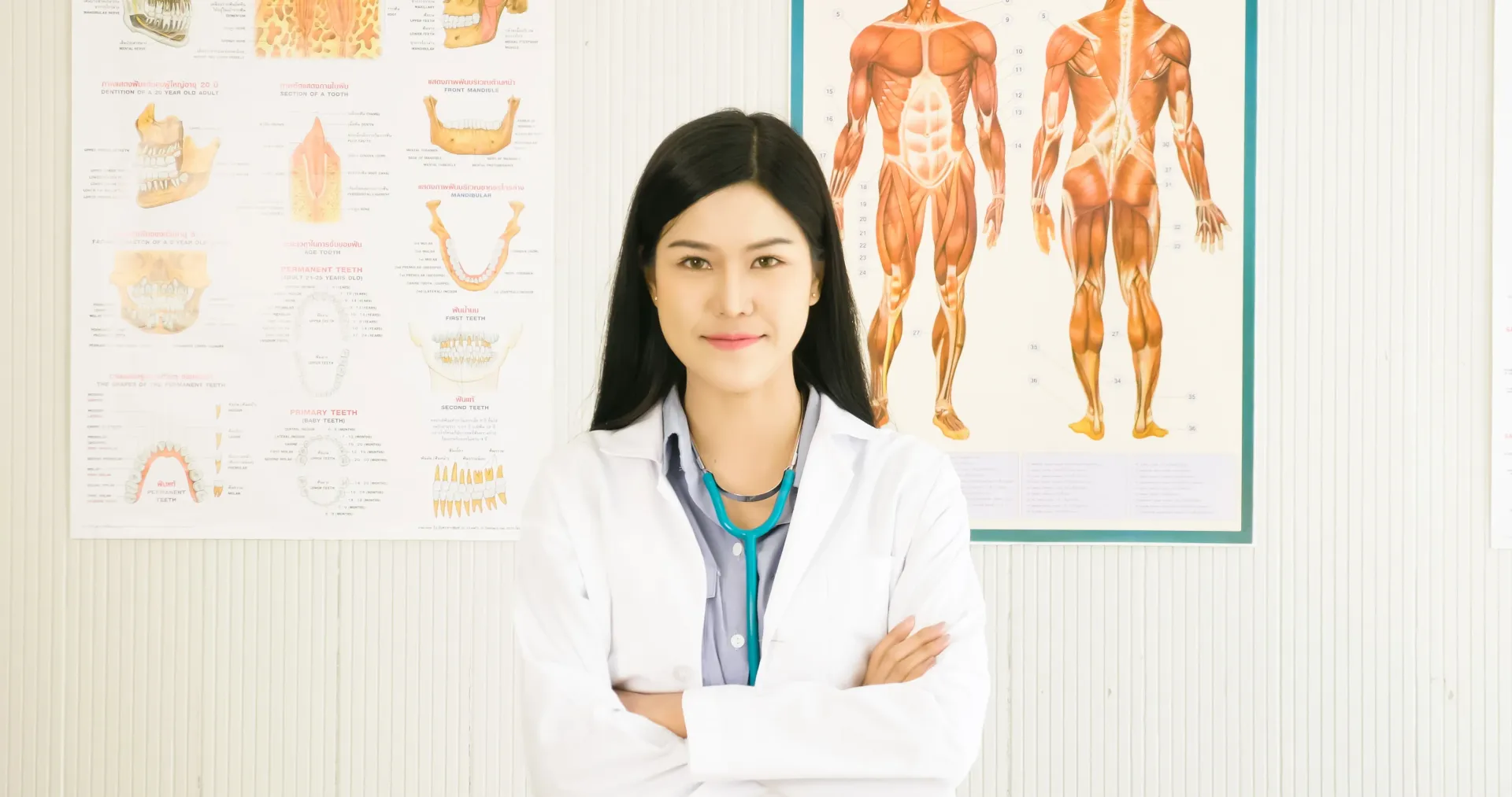 Consulta dermatológica para diagnóstico do CID L98 Médico com os braços cruzados, vestindo jaleco branco e estetoscópio, em um consultório médico com prontuários.