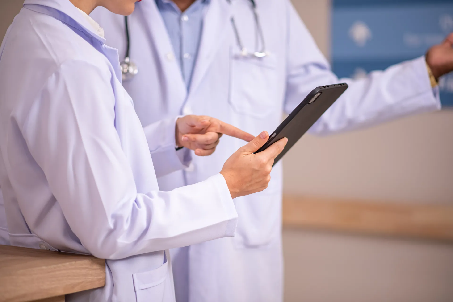 Sistema de controle de orçamentos para clínicas e consultórios. Dois médicos de jaleco branco examinando um tablet em um ambiente hospitalar.