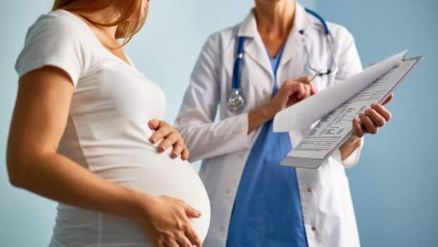 Gestante e médico revisando documentos médicos.
