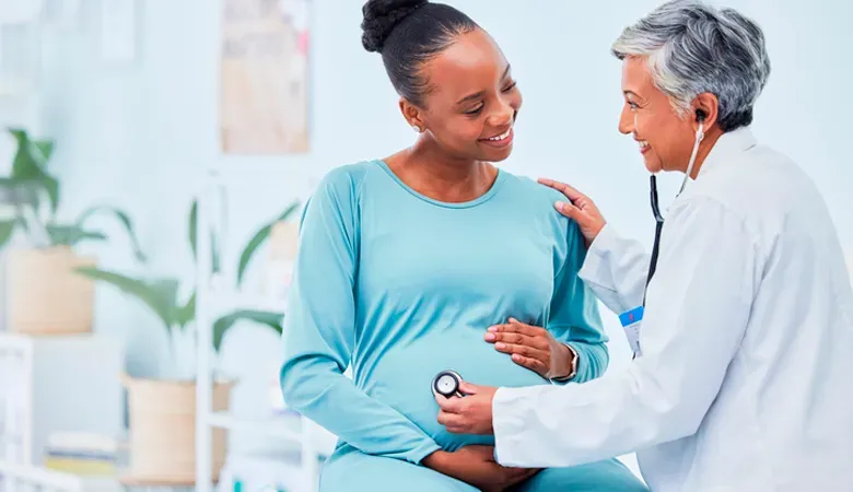 Mulher grávida sendo examinada por um médico com um estetoscópio.
