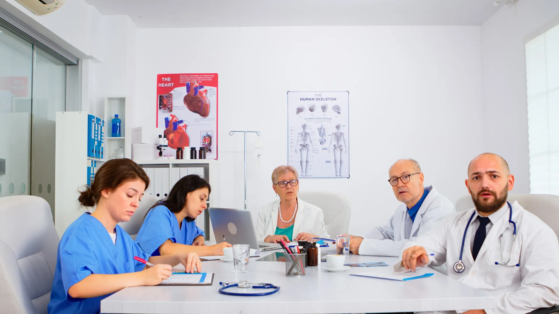 Equipe médica reunida, revisando prontuários e discutindo casos em um escritório bem iluminado.