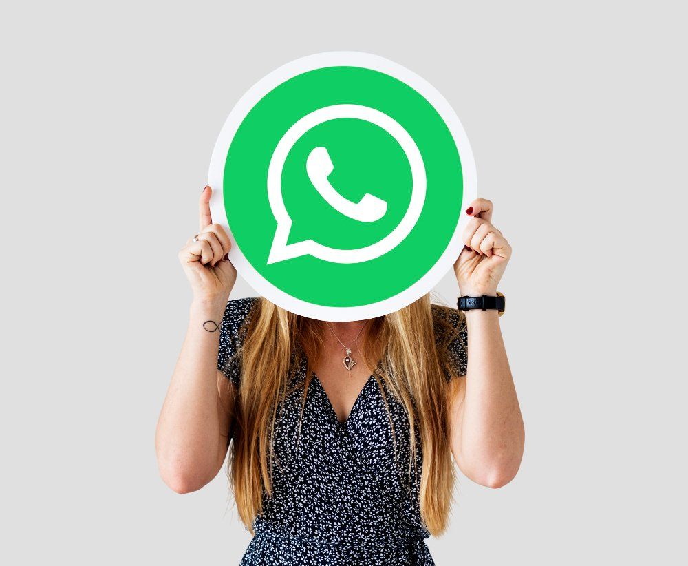 Mulher segurando um logotipo verde do WhatsApp em frente ao rosto.