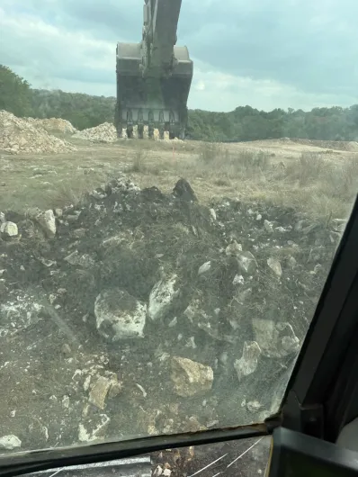 A yellow excavator is digging a hole in the ground.