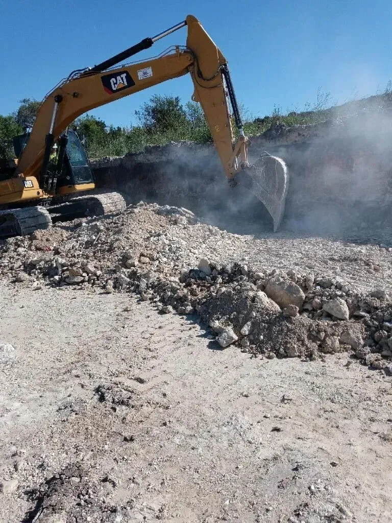 A cat excavator is digging a hole in the dirt.