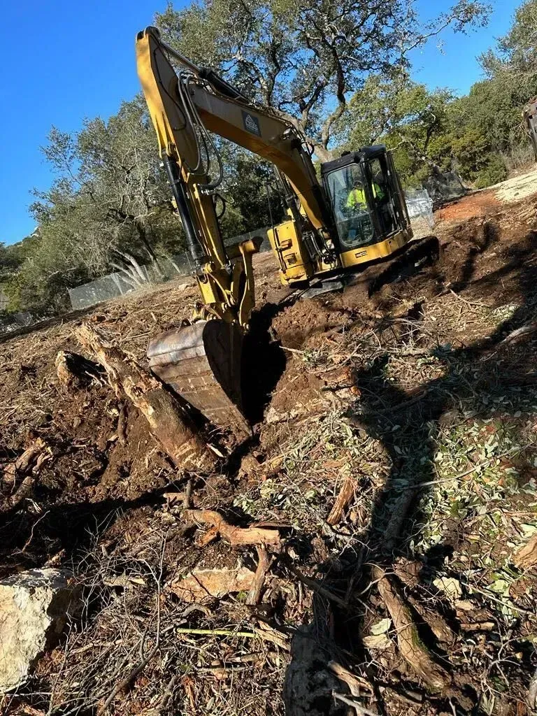 A large yellow excavator is digging a hole in the ground.