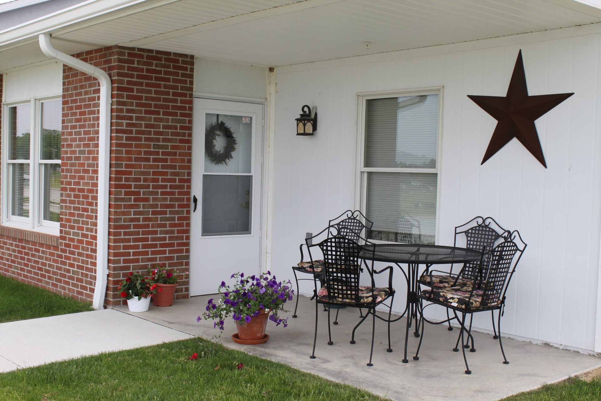 Covered porch with metal patio set, star decor, and brick accents.