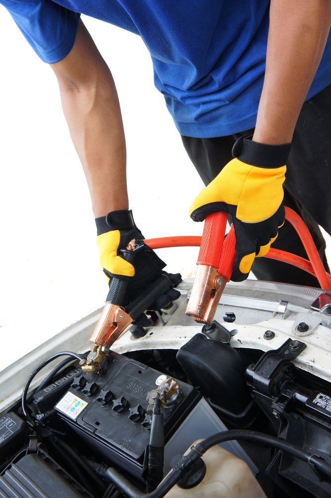 Person Wearing Yellow Gloves Connects Jumper Cables to a Car Battery — Great Western Auto Wreckers in Orange, NSW