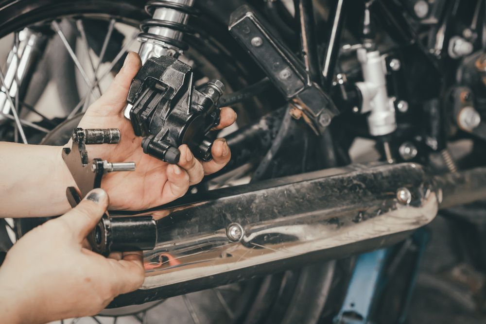 Person Working on a Motorcycle Brake Caliper — Great Western Auto Wreckers in Orange, NSW
