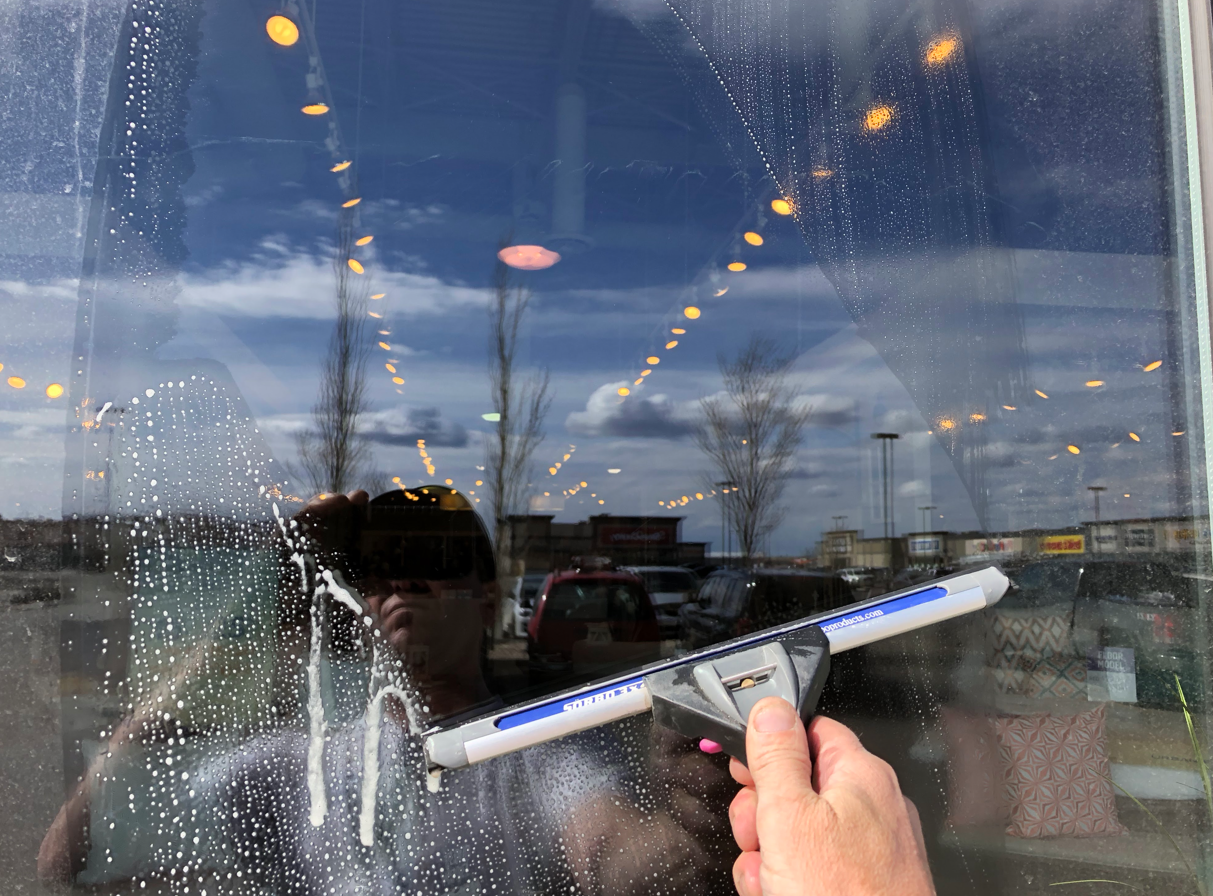 A person is cleaning a window with a squeegee.