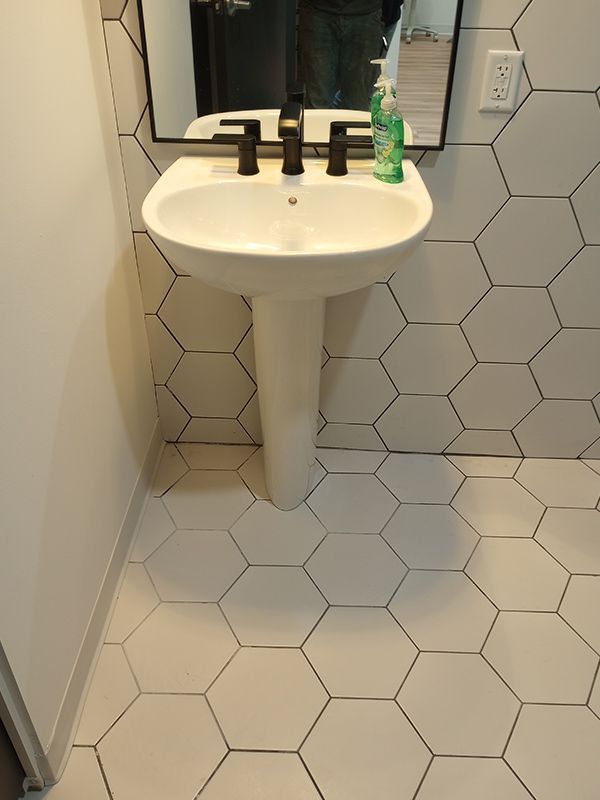 A bathroom sink with a hexagonal tile floor and a mirror.