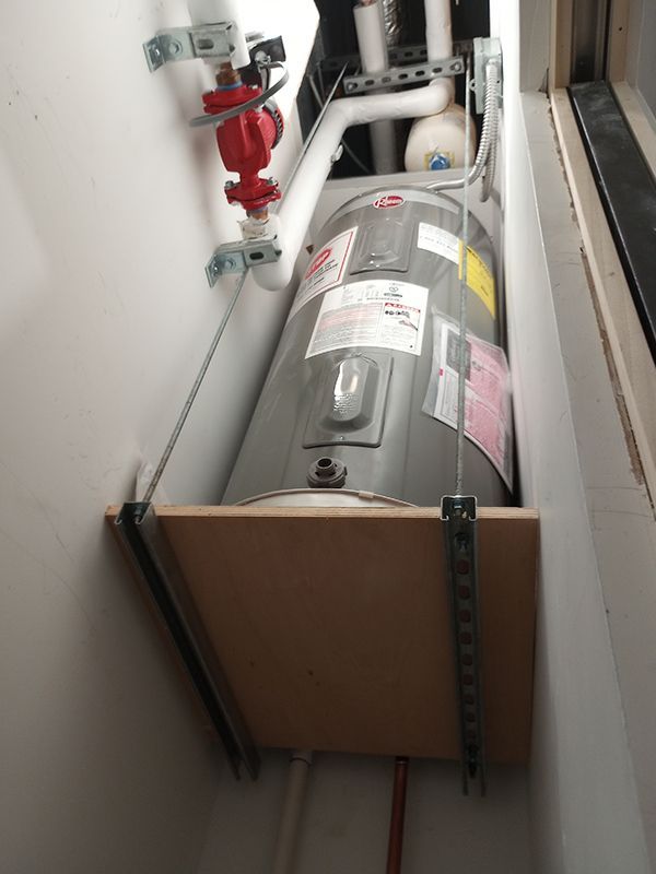 A water heater is sitting on top of a wooden box.