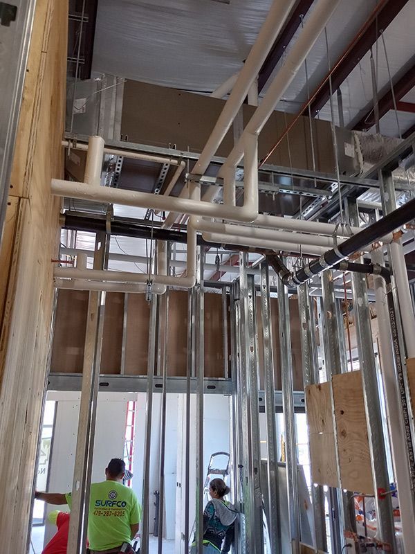 A man in a green shirt is standing in a building under construction.