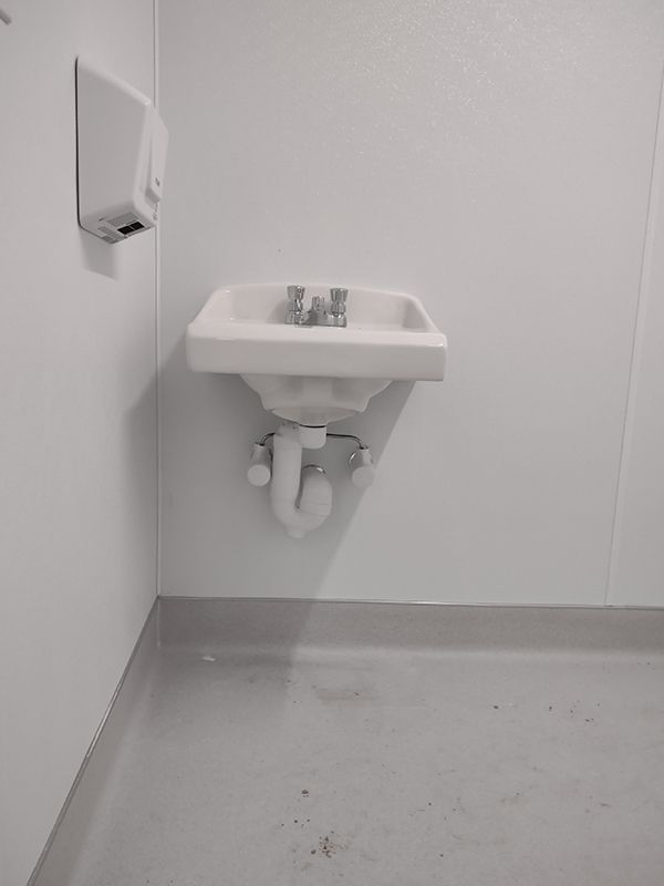 A white sink is hanging on a white wall in a bathroom.