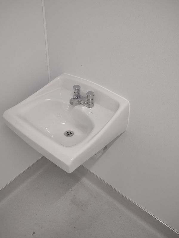 A white sink is hanging on a white wall in a bathroom.