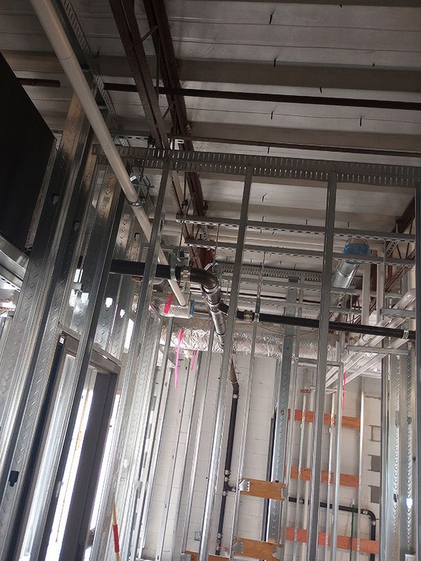 A building under construction with a lot of pipes hanging from the ceiling.
