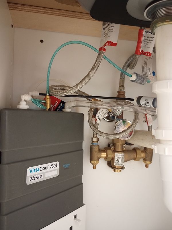 A kitchen sink with a lot of pipes underneath it.