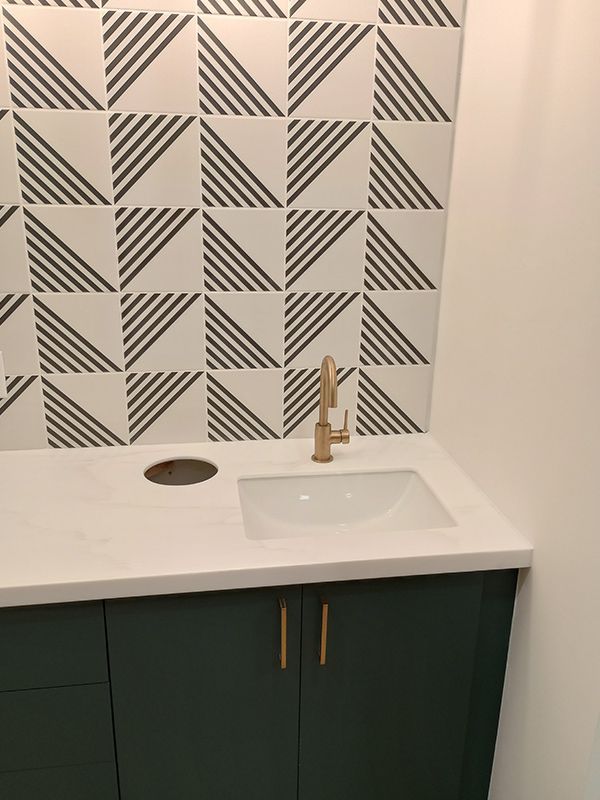 A sink with a geometric pattern on the wall behind it
