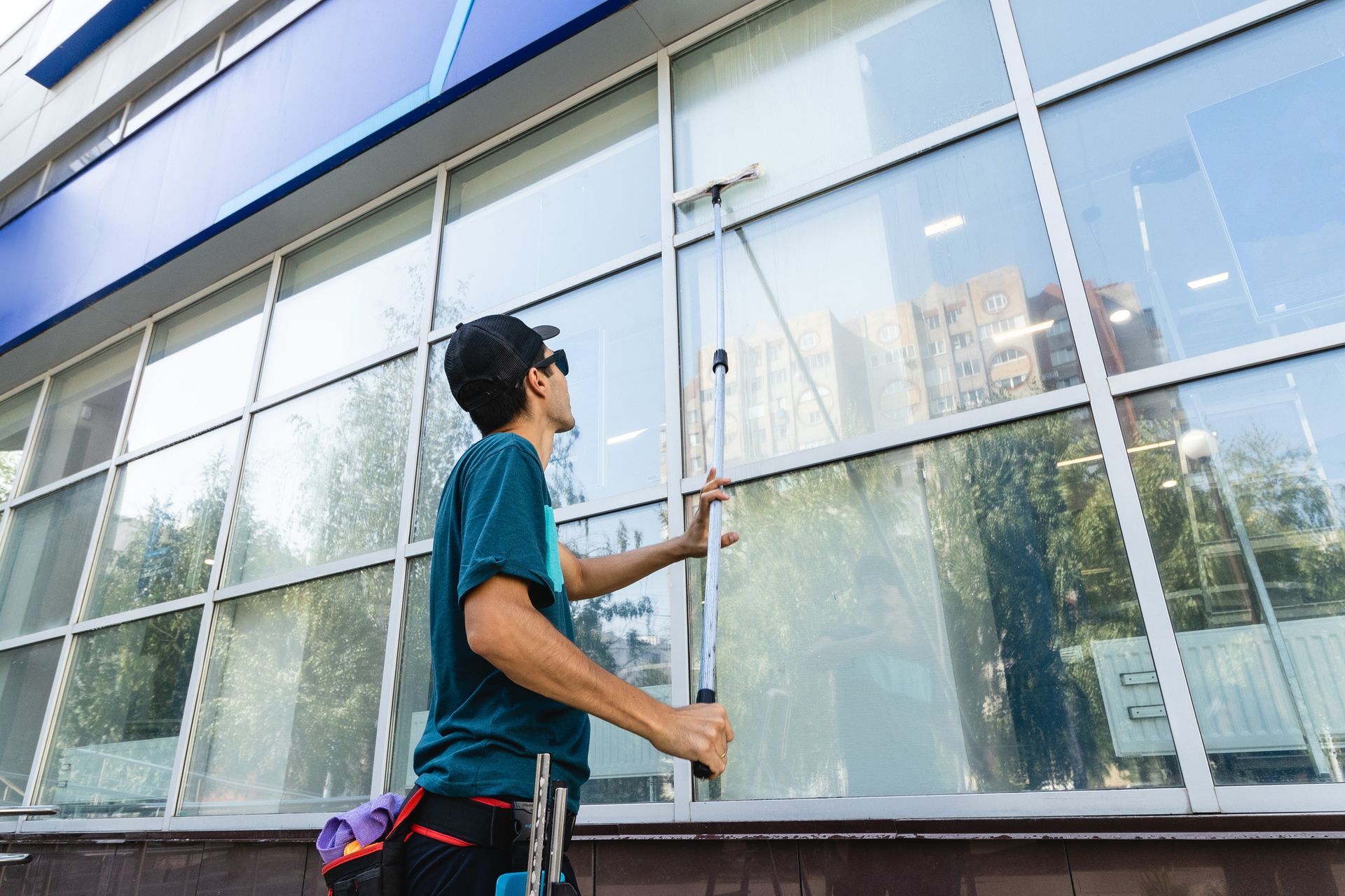 Person cleaning large glass windows on a building exterior with a squeegee