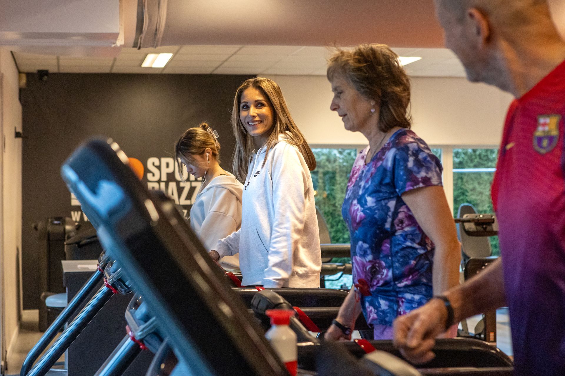 Een groep mensen loopt op loopbanden in een sportschool.
