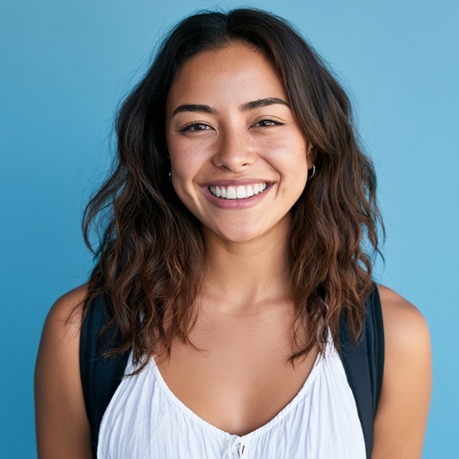Smiling person with wavy dark hair wearing a white top against a blue background