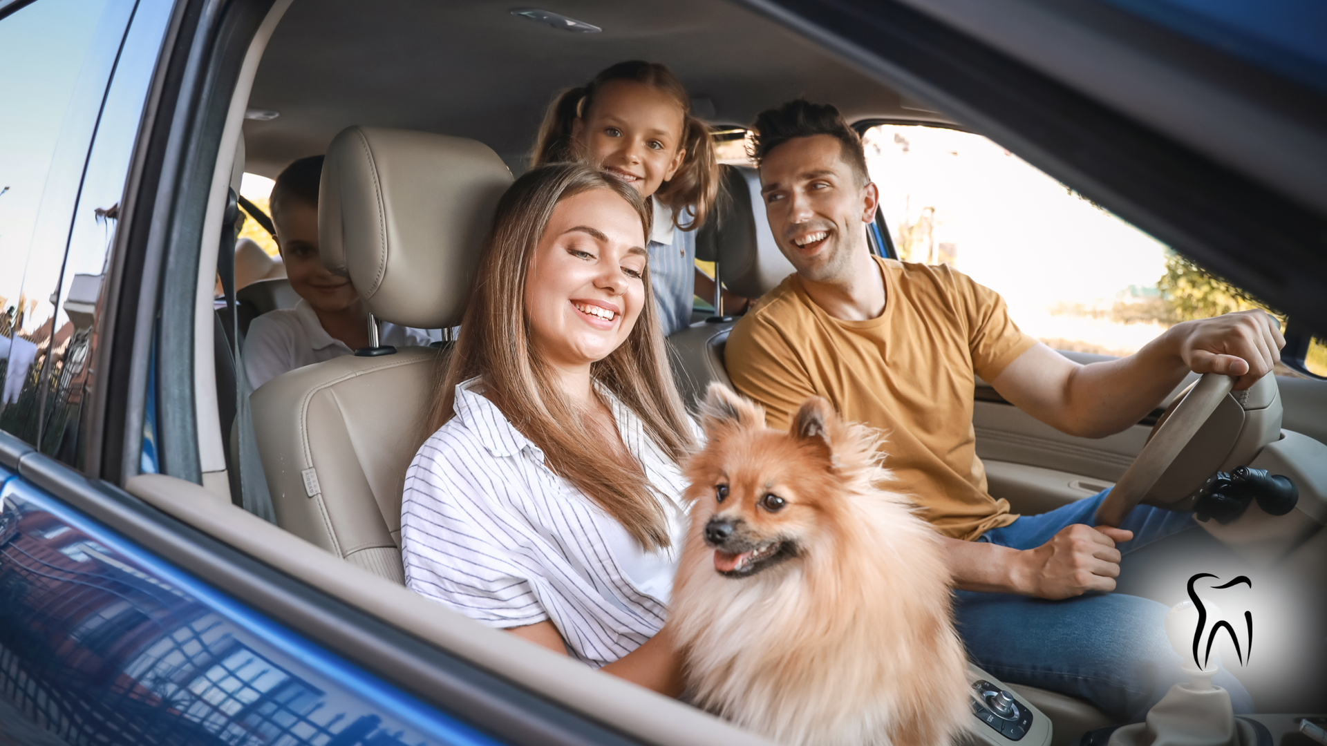 Family in car, with dog, smiling; sunny day.