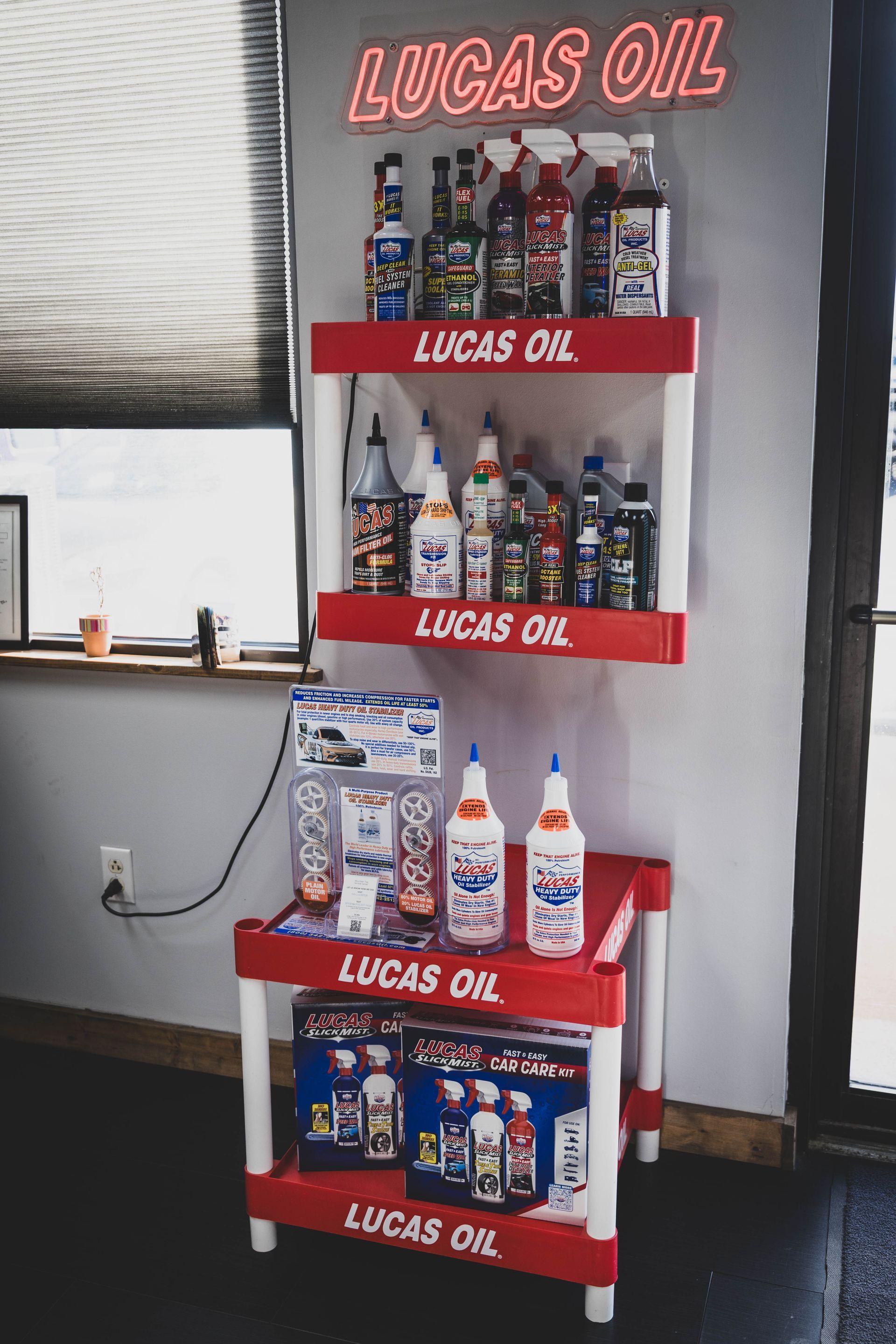 A Lucas Oil product display with red shelves against a gray wall. Illuminated 