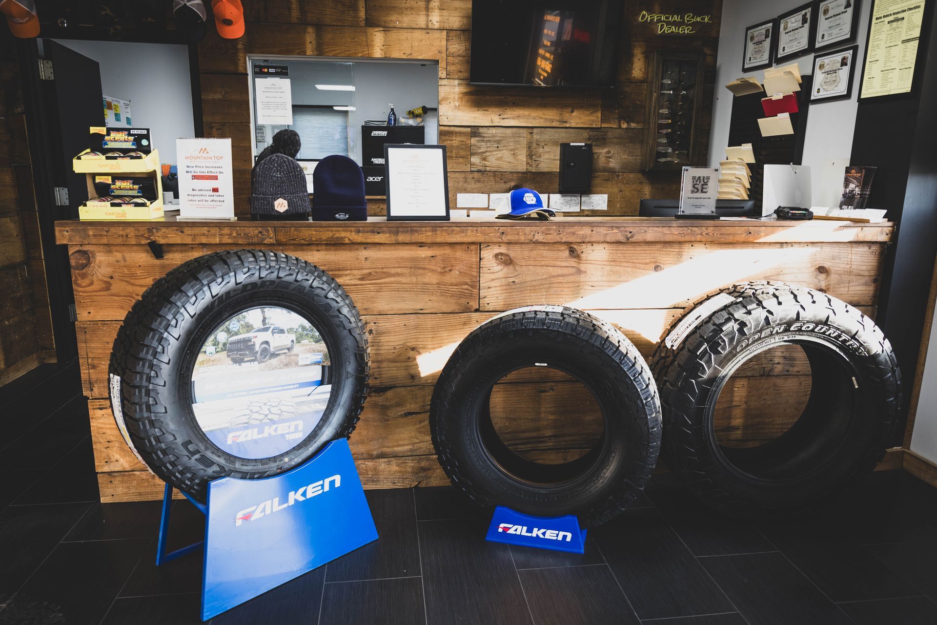 Tires on display in a shop, with a wooden counter and a person in the background. 