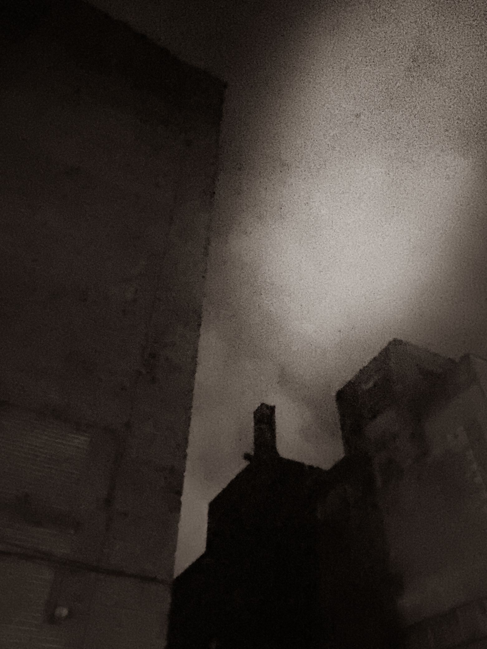 Dark buildings against a grainy sky, viewed from a low angle.