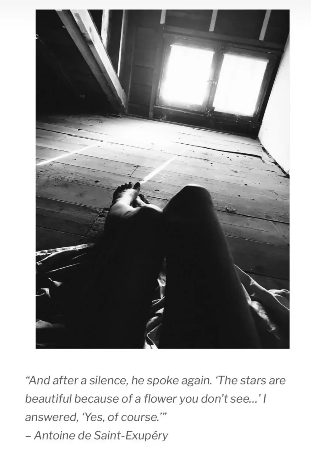 Black and white photo: legs of a person looking up at a window in an attic, text from Antoine de Saint-Exupéry below.