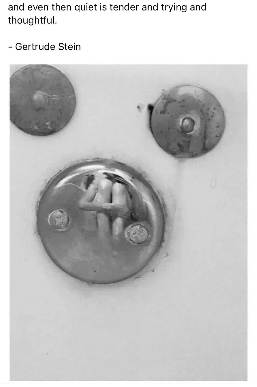 Three metal fixtures on a white surface, resembling buttons or knobs, one with a small handle.
