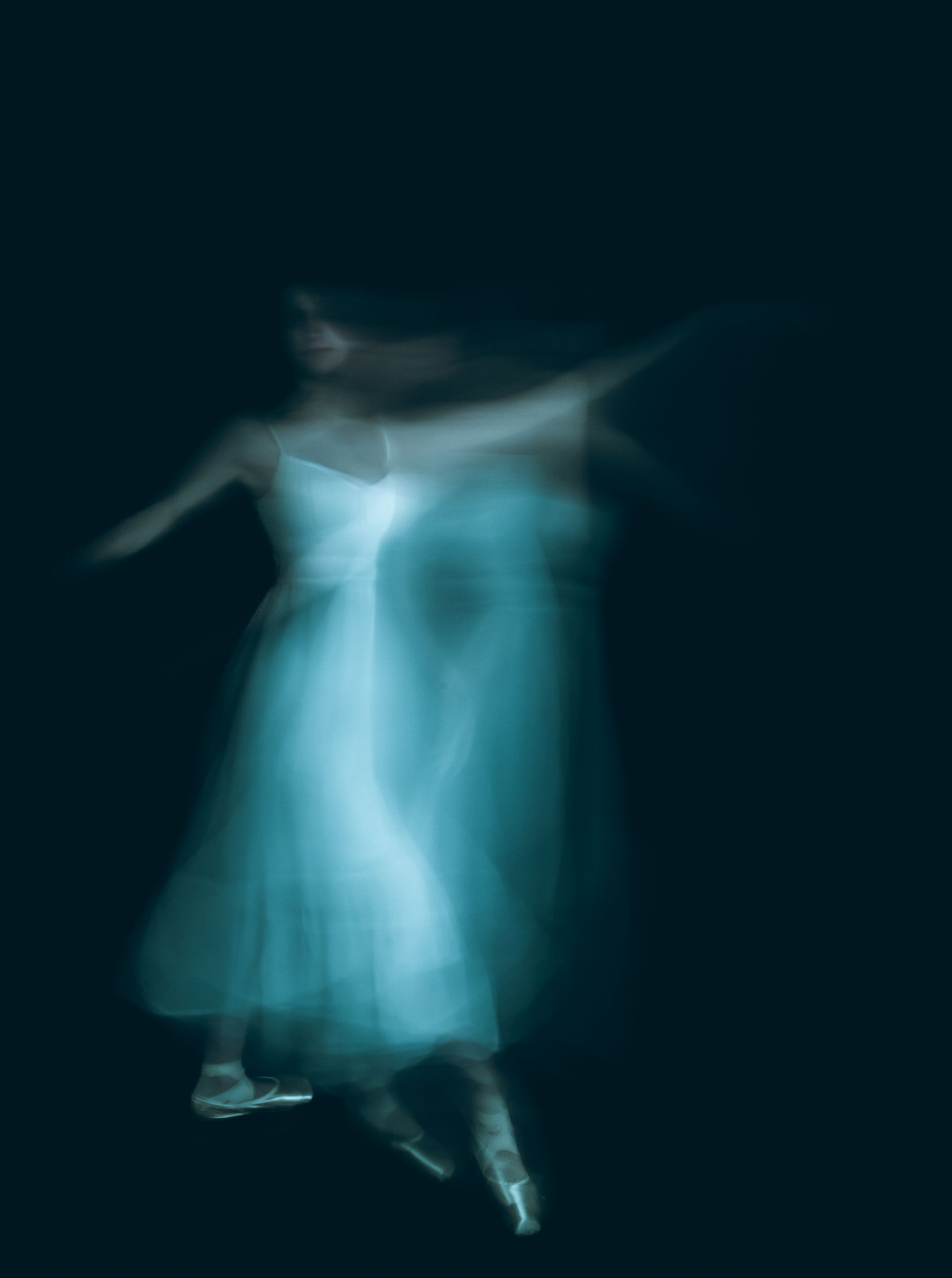 Ballerina in white dress, blurred motion, arms extended, turquoise glow against a dark background.