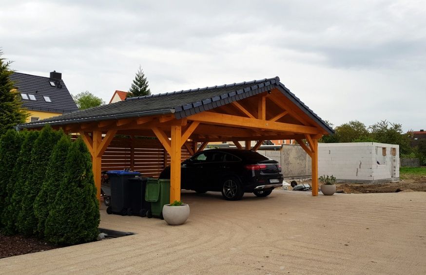 A Car Is Parked Under A Wooden Carport In A Driveway — Chris Stolk Constructions In Kanahooka, NSW