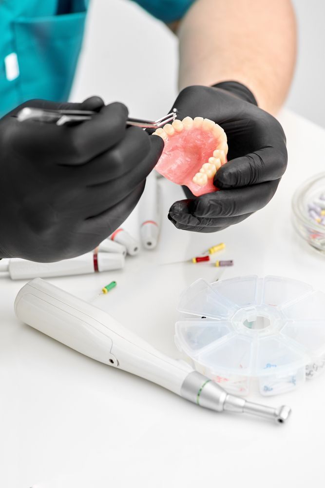 A Dentist is Working on a Denture With a Pair of Scissors — Bromley's Denture Clinic in Tweed Heads, NSW