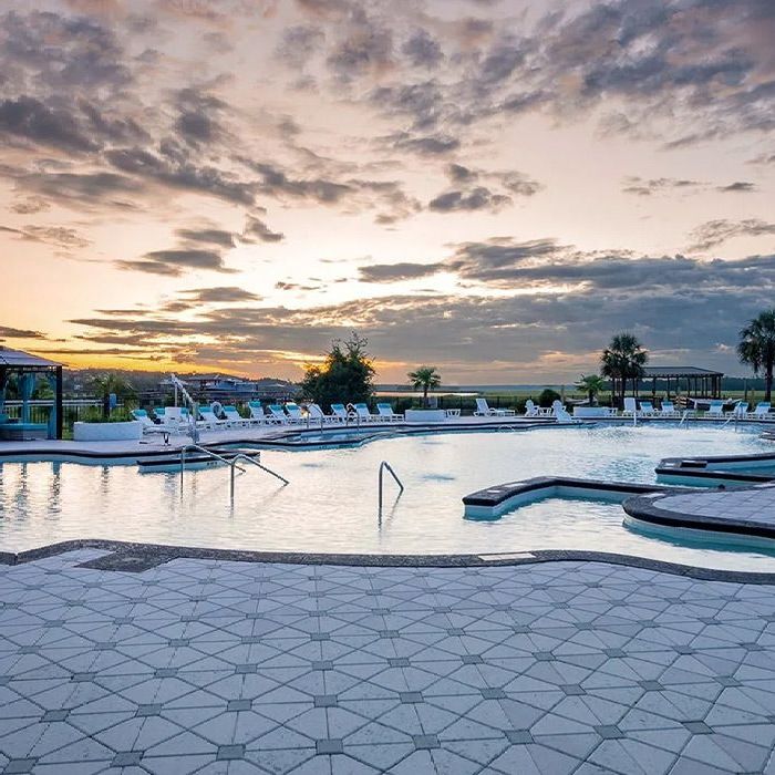 A large swimming pool with a sunset in the background.