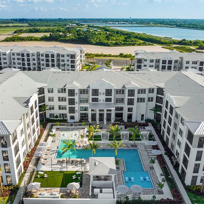 An aerial view of a large apartment building with a large swimming pool