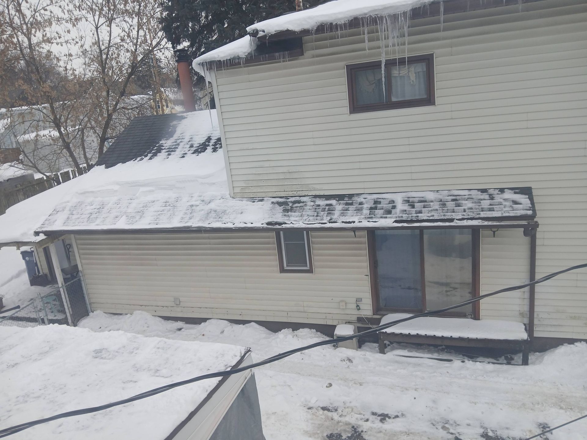 Snow-covered house with white siding and a small porch in a winter yard.
