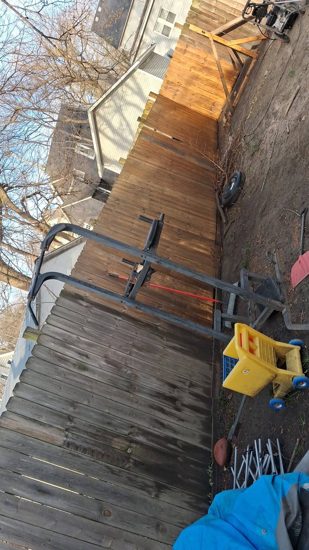 Backyard with wooden fence, patio furniture, and a yellow toy on gravel under bare trees
