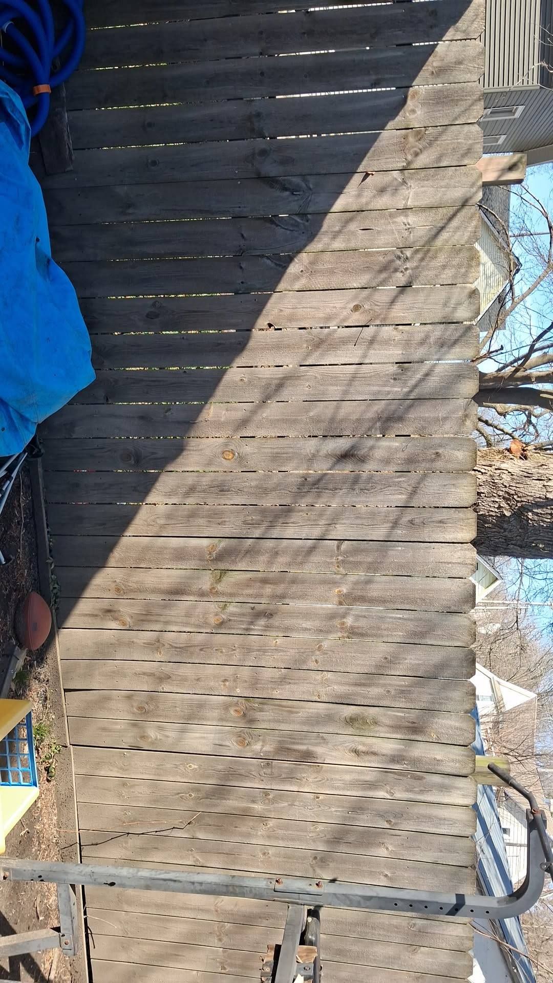 Wooden deck with snow patches and a blue tarp on the left, outdoors in winter.
