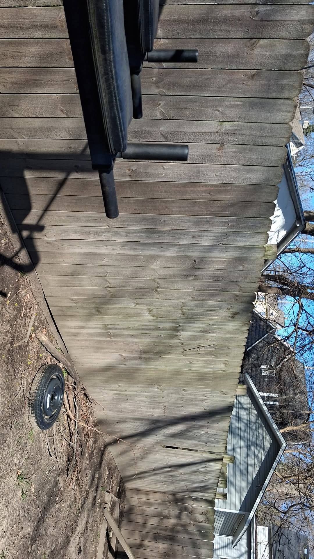 Winter backyard with wooden fence, bare trees, and a deck railing under a blue sky