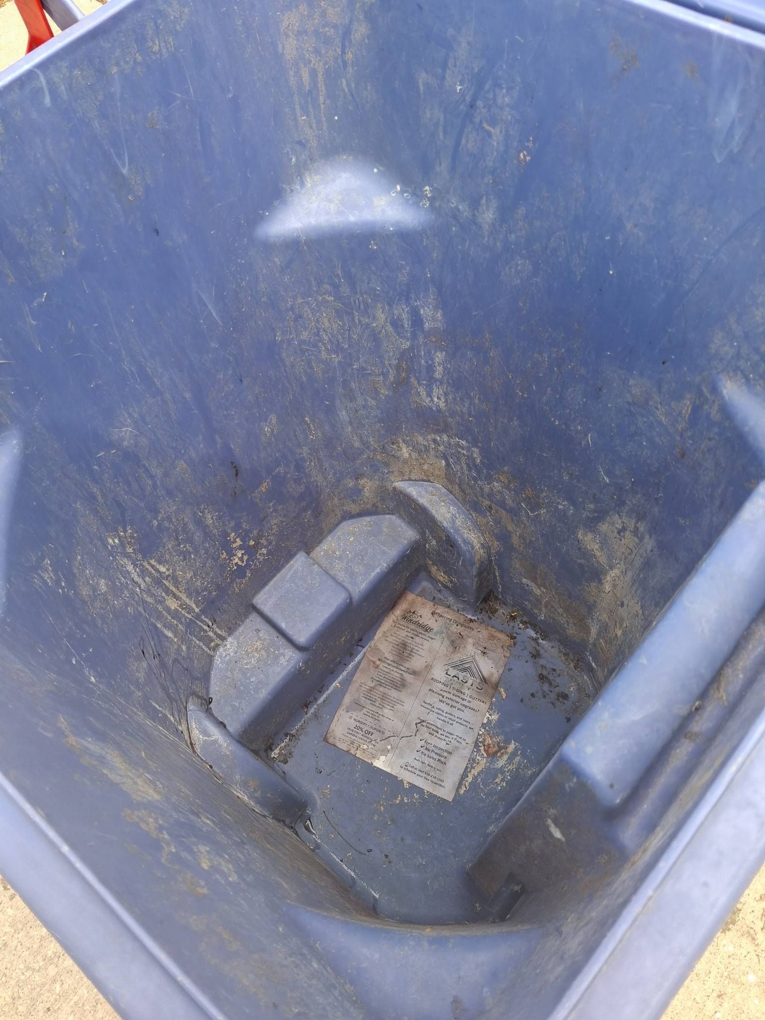 Empty blue plastic bin with dirt and debris at the bottom
