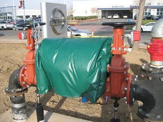 a green tarp is covering a fire hydrant in front of a nissan sign
