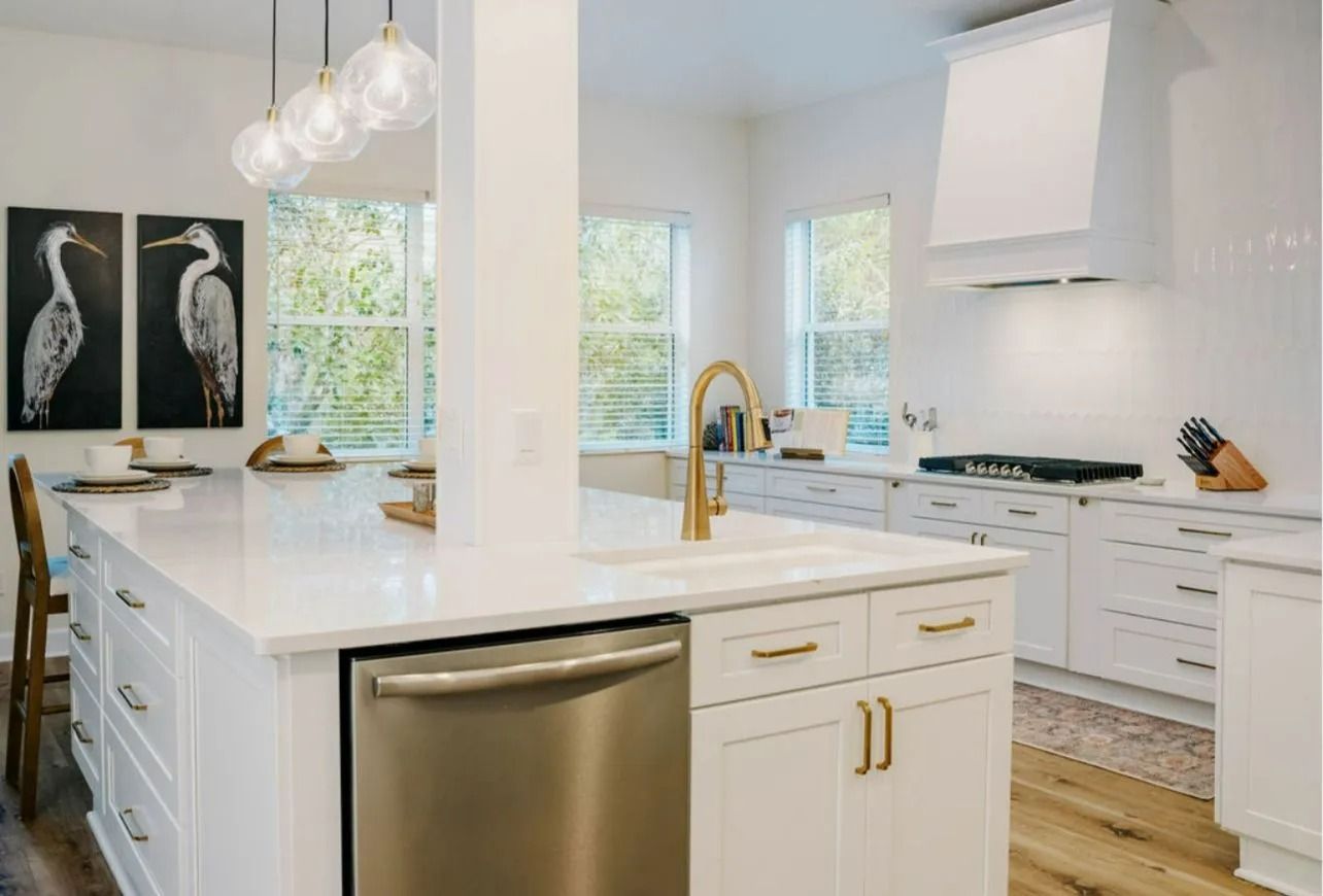 A kitchen with white cabinets , stainless steel appliances , and a large island.