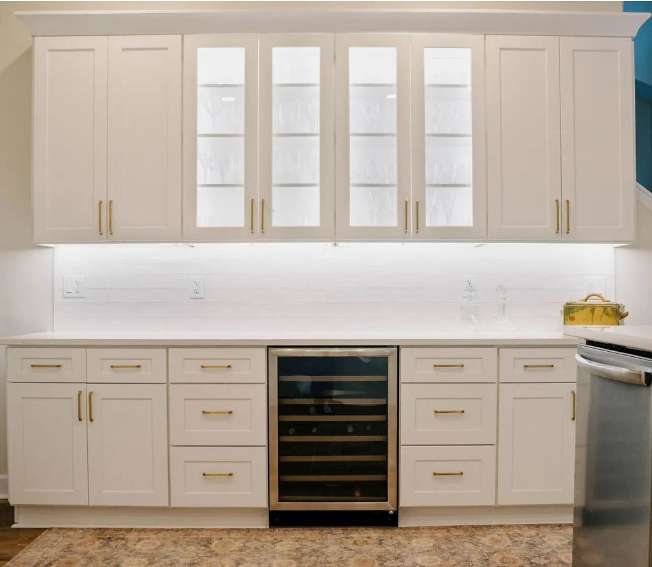 A kitchen with white cabinets and a wine cooler