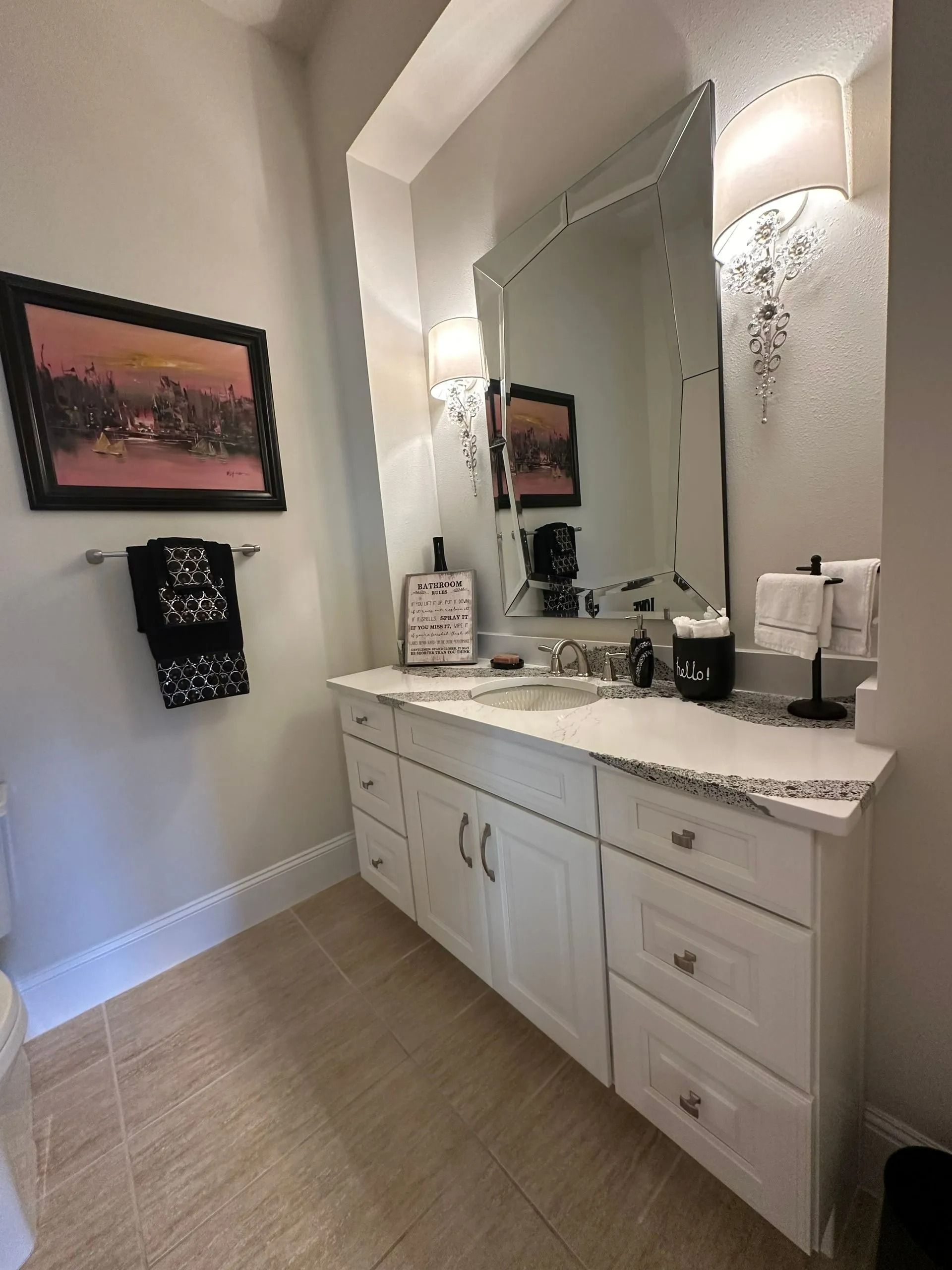 A bathroom with white cabinets and a large mirror