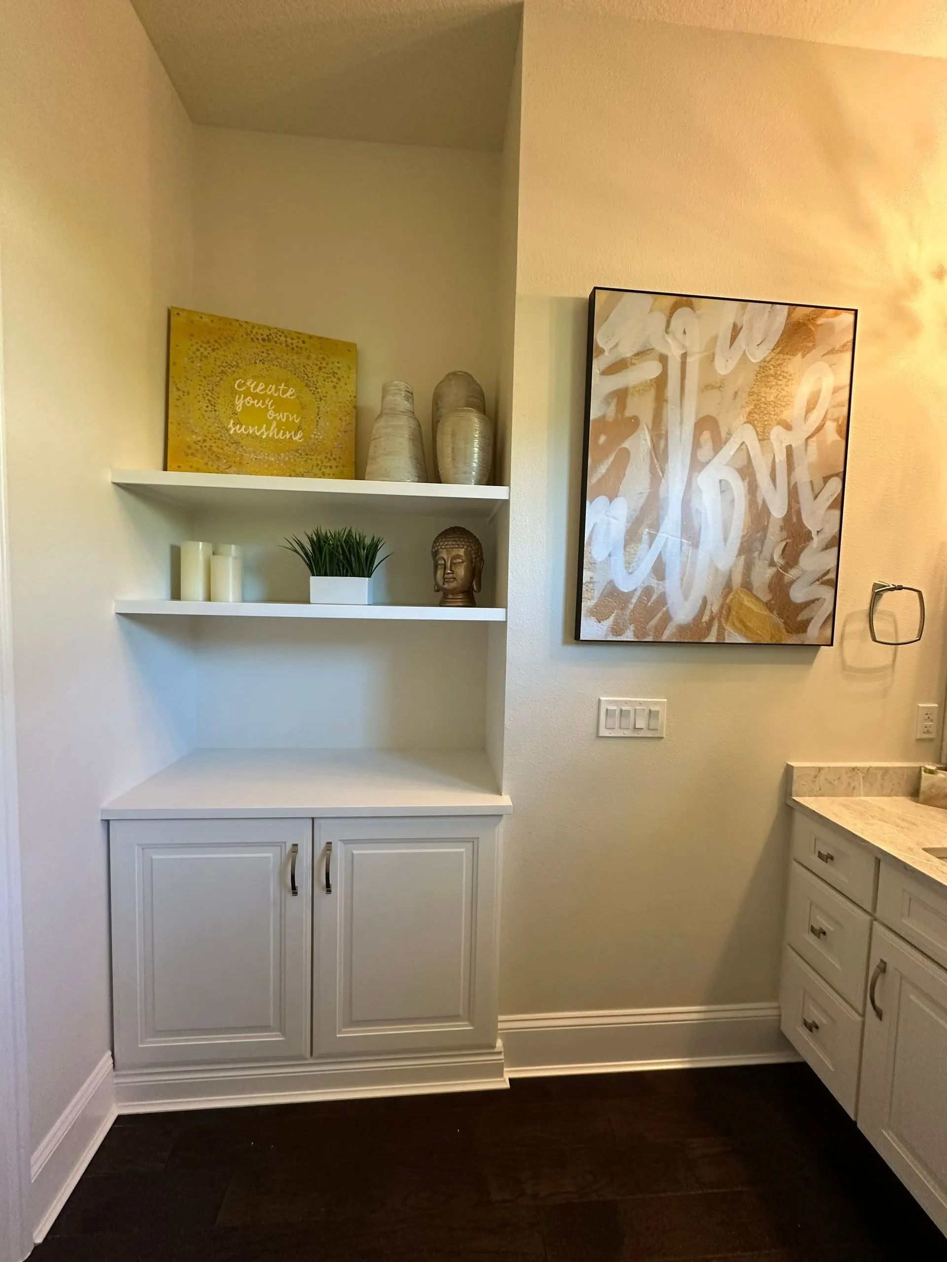 A bathroom with white cabinets and a painting on the wall