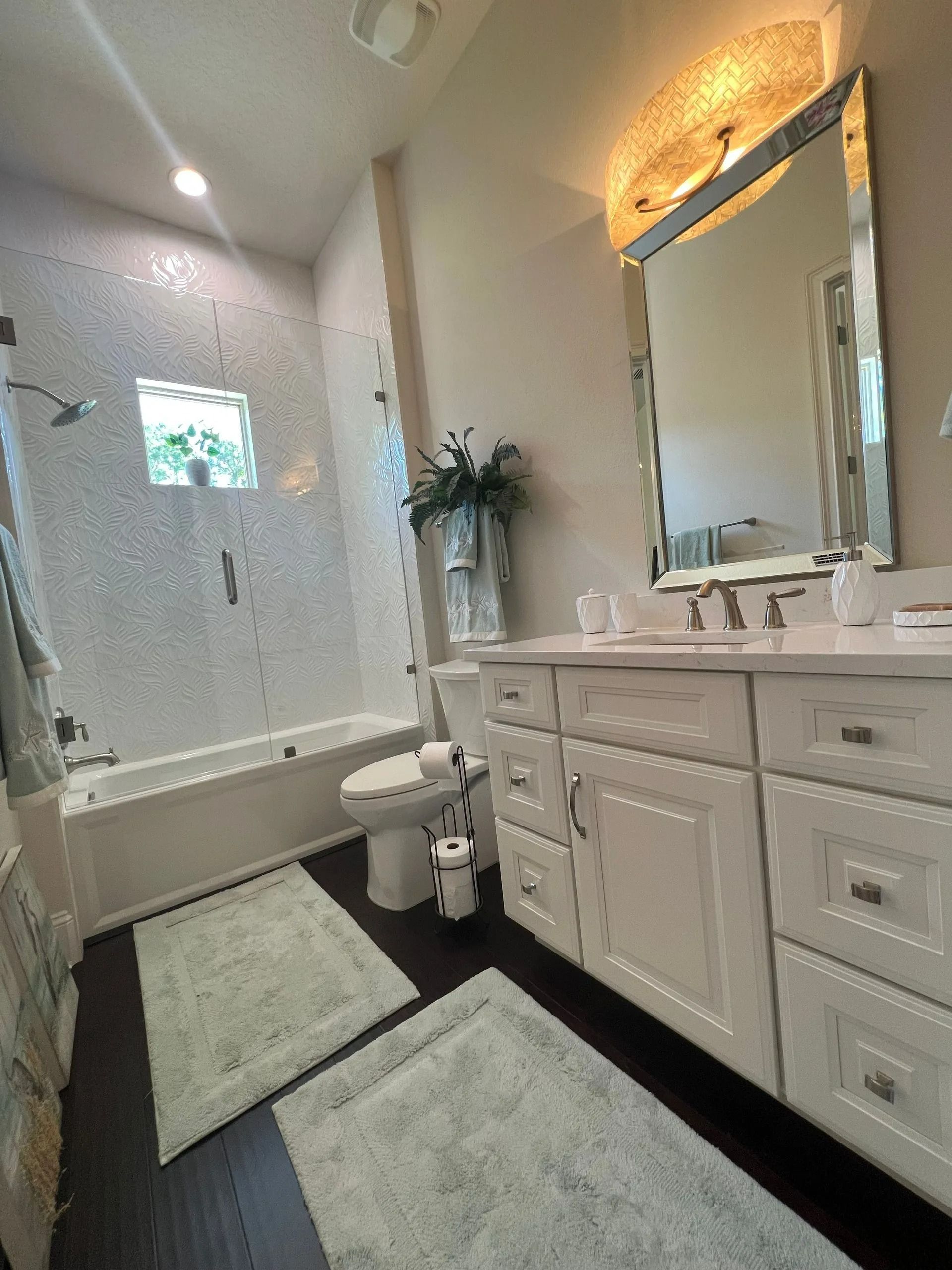 A bathroom with a toilet , sink , tub and mirror.