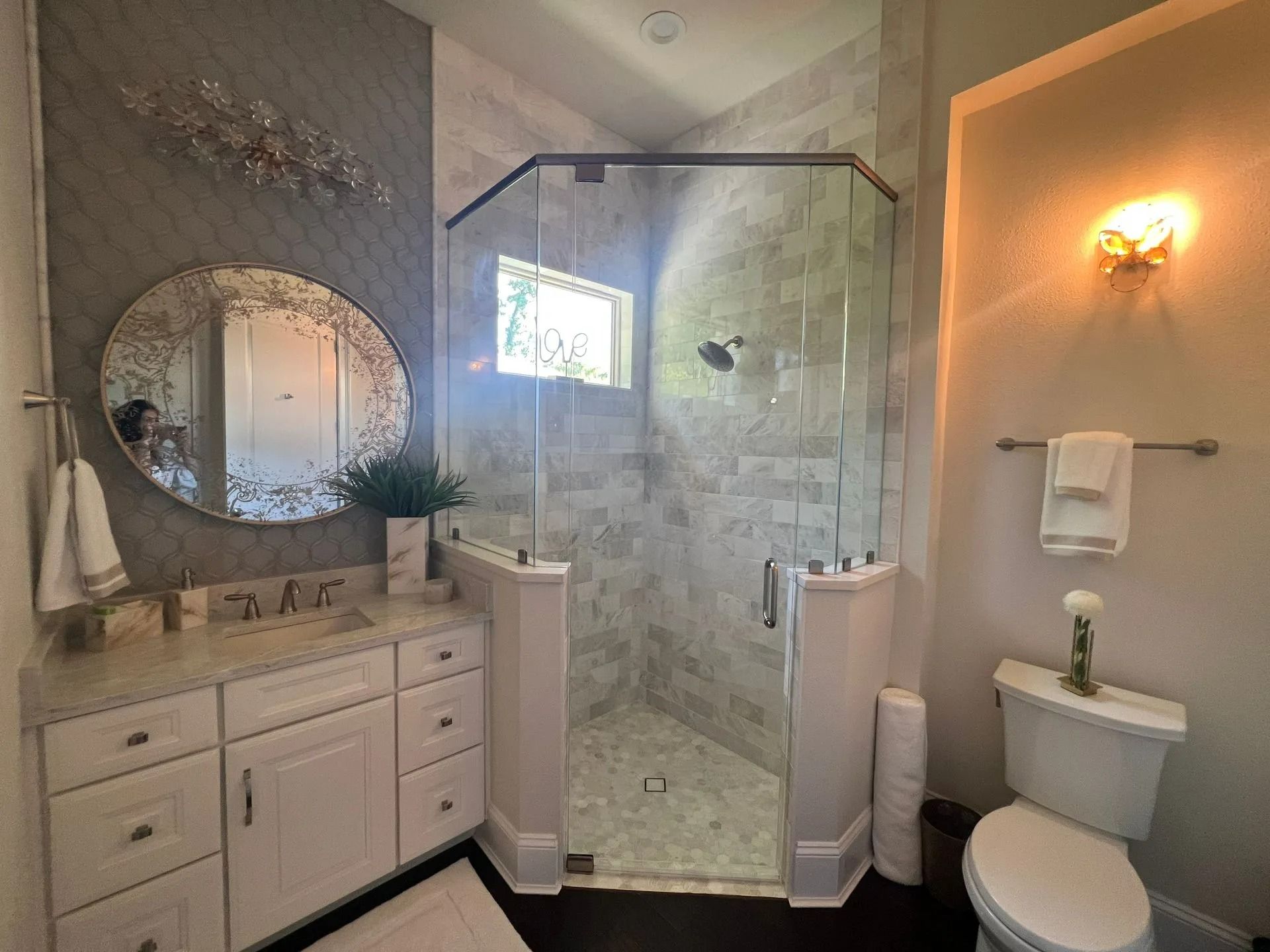 A bathroom with a toilet , sink , mirror and walk in shower.
