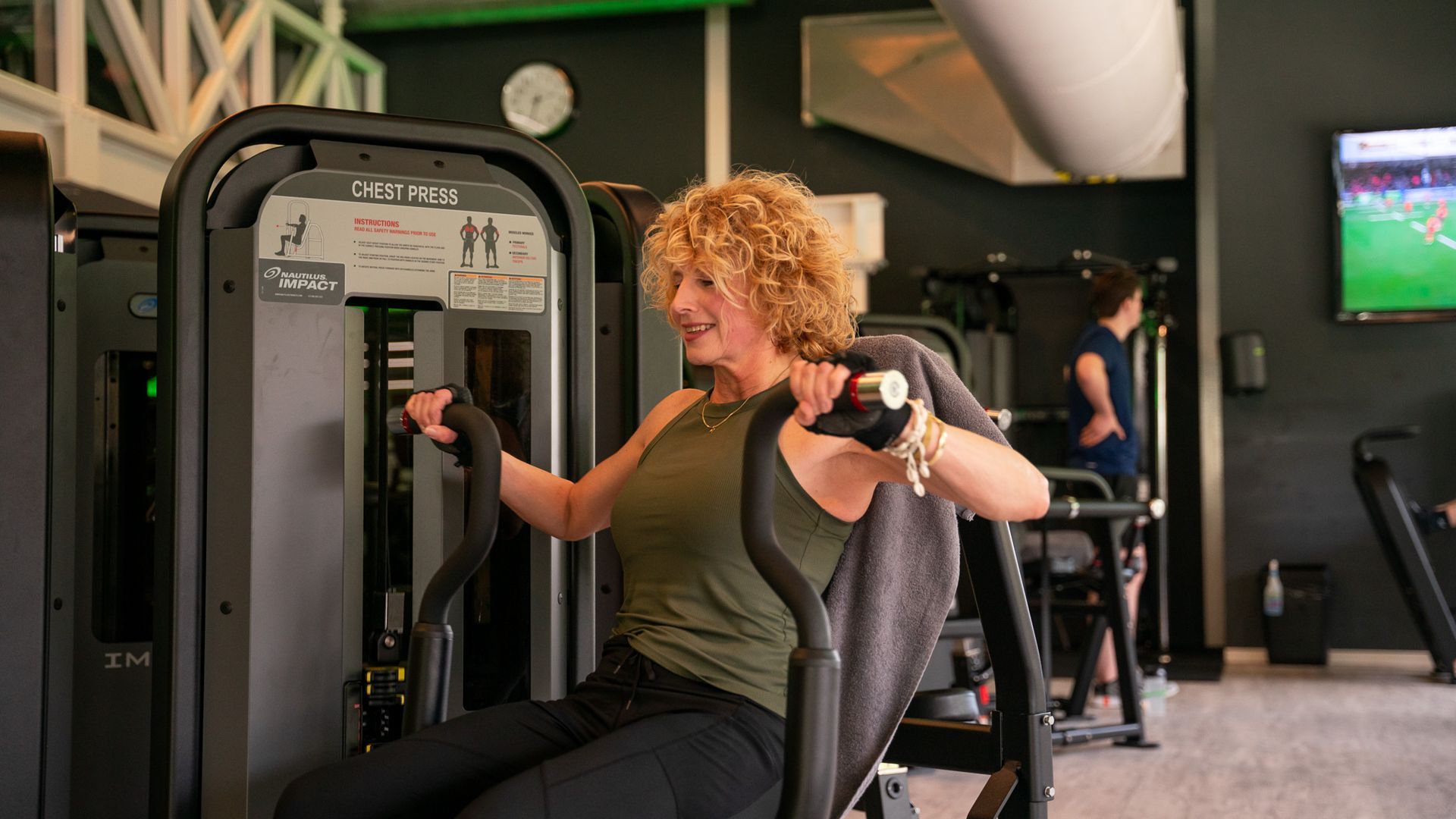 Een gymzaal vol met fitnessapparatuur en een blauwe baan.