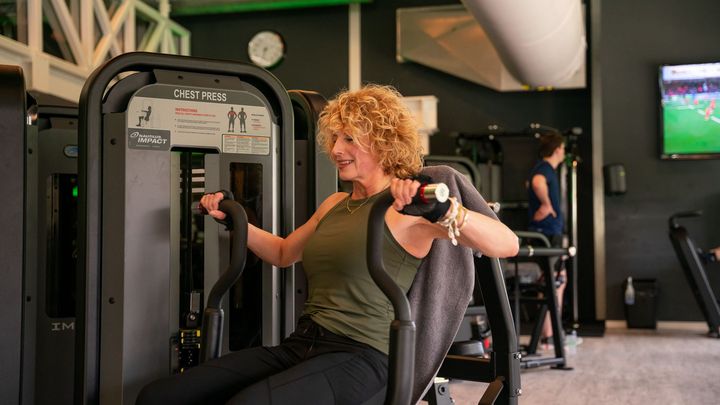 Een gymzaal vol met fitnessapparatuur en een blauwe baan.